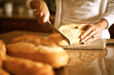 Rediscovering Bread 4 Woman slicing bread Rediscovering Bread - EAT LOVE SAVOR International Luxury Lifestyle Magazine